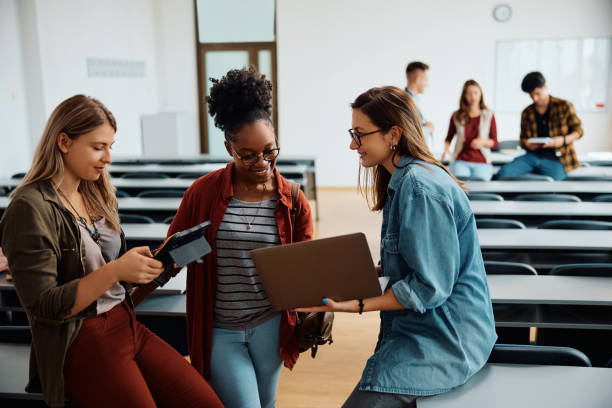 Multiracial group of female students using wireless technology in university classroom.